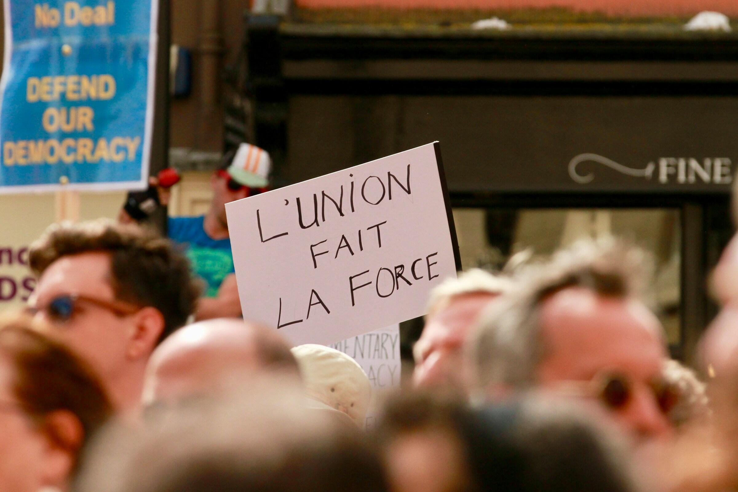 Placa escrita "A união faz a força" em meio à multidão de franceses.