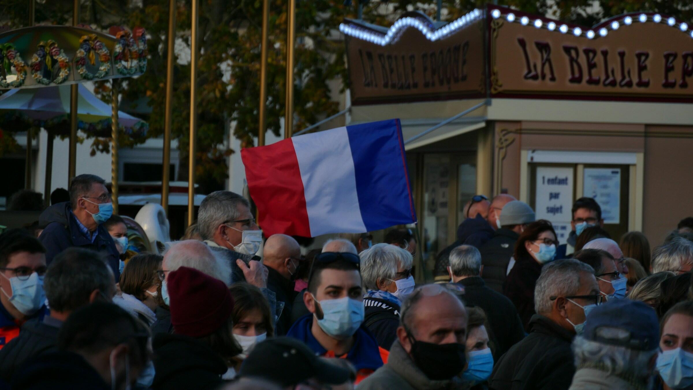 Pessoas na rua com a bandeira da França.