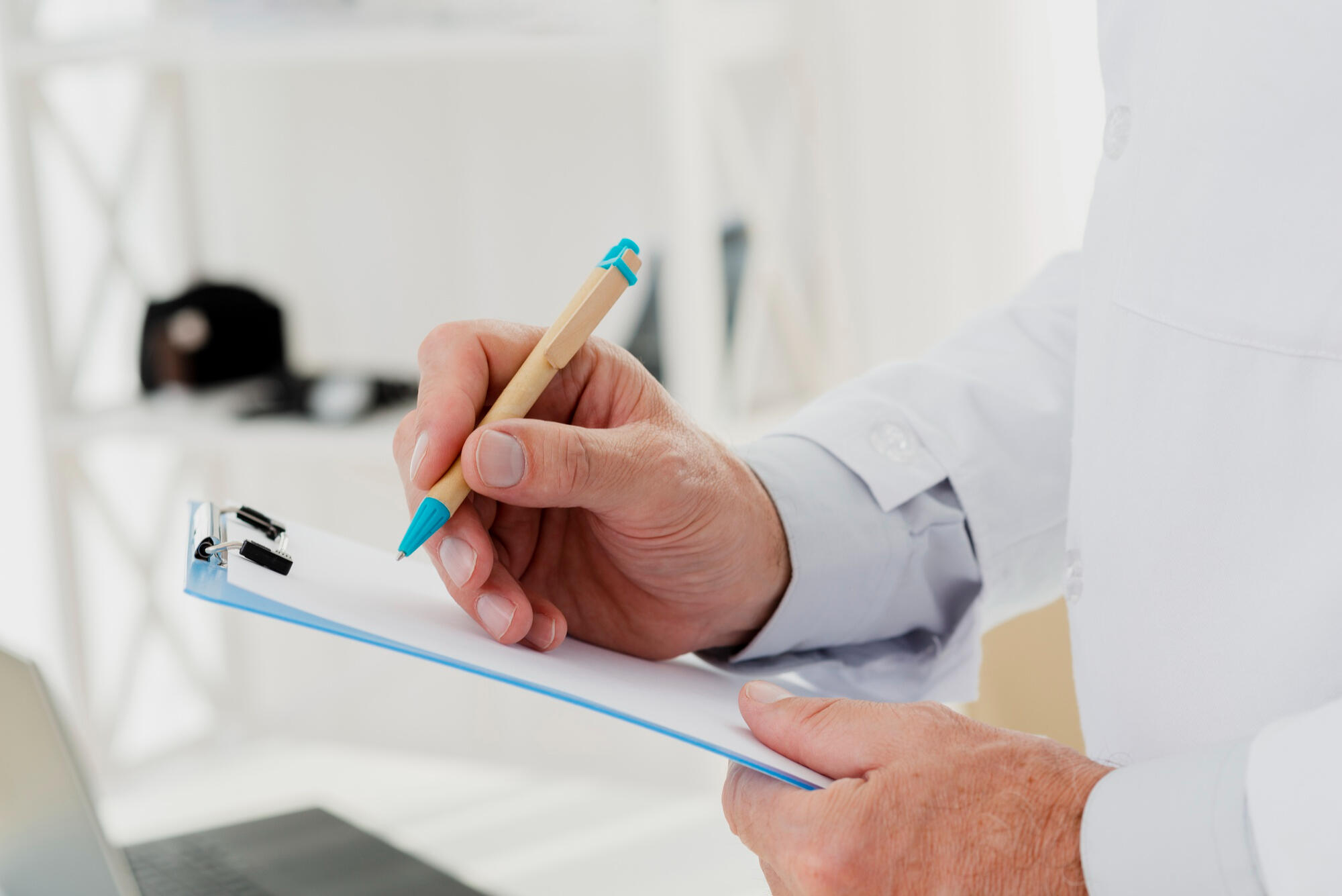 Médico escrevendo na prancheta.