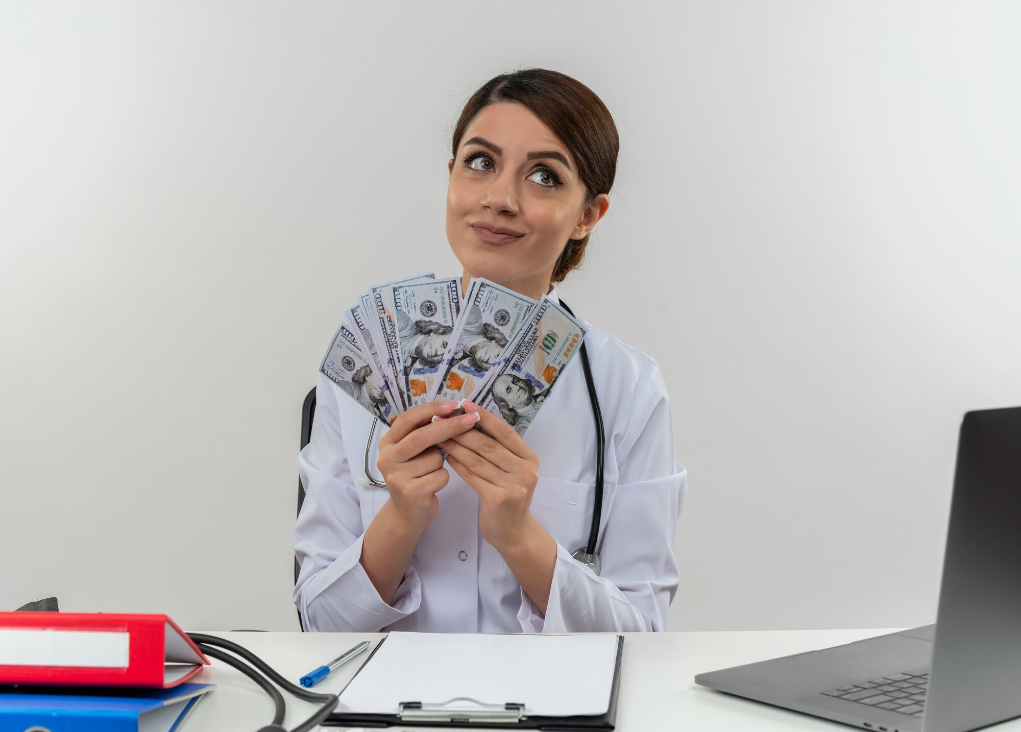 Médica com dinheiro na mão sentada na mesa.