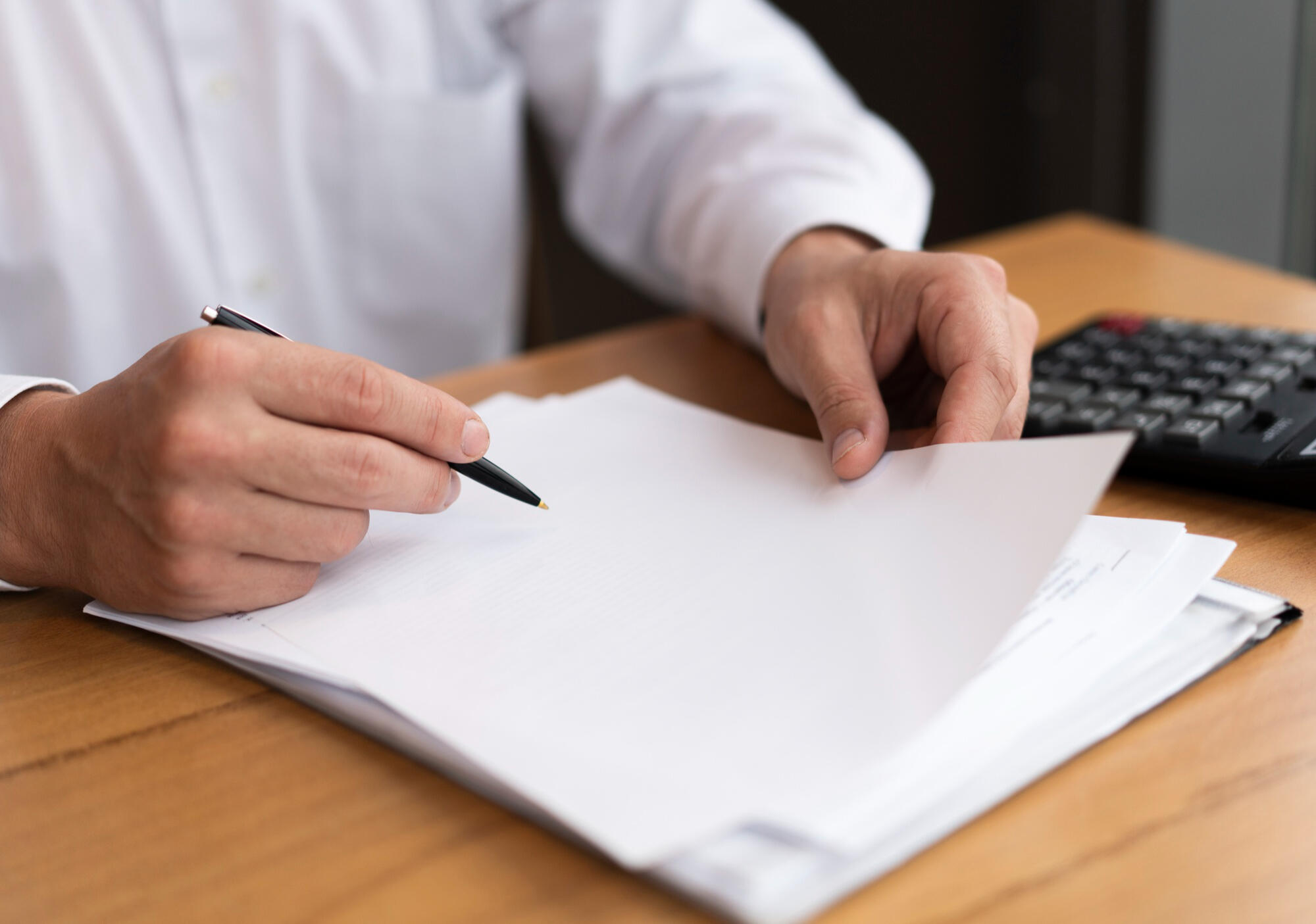 Advogando calculando a prescrição penal, segurando papel e caneta, com calculadora do lado. 