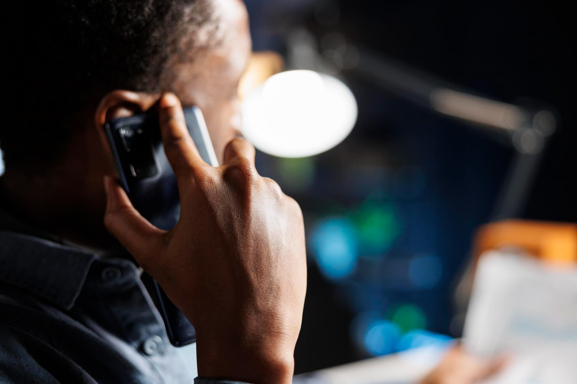 Profissional atendendo ao telefone com computador à frente.