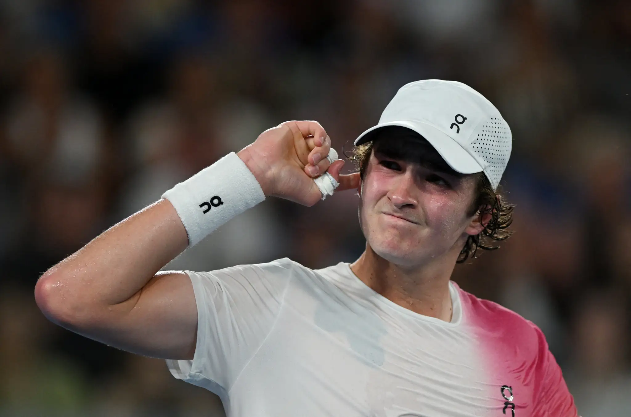 Tenista João Fonseca apontando o dedo para a cabeça durante a partida.