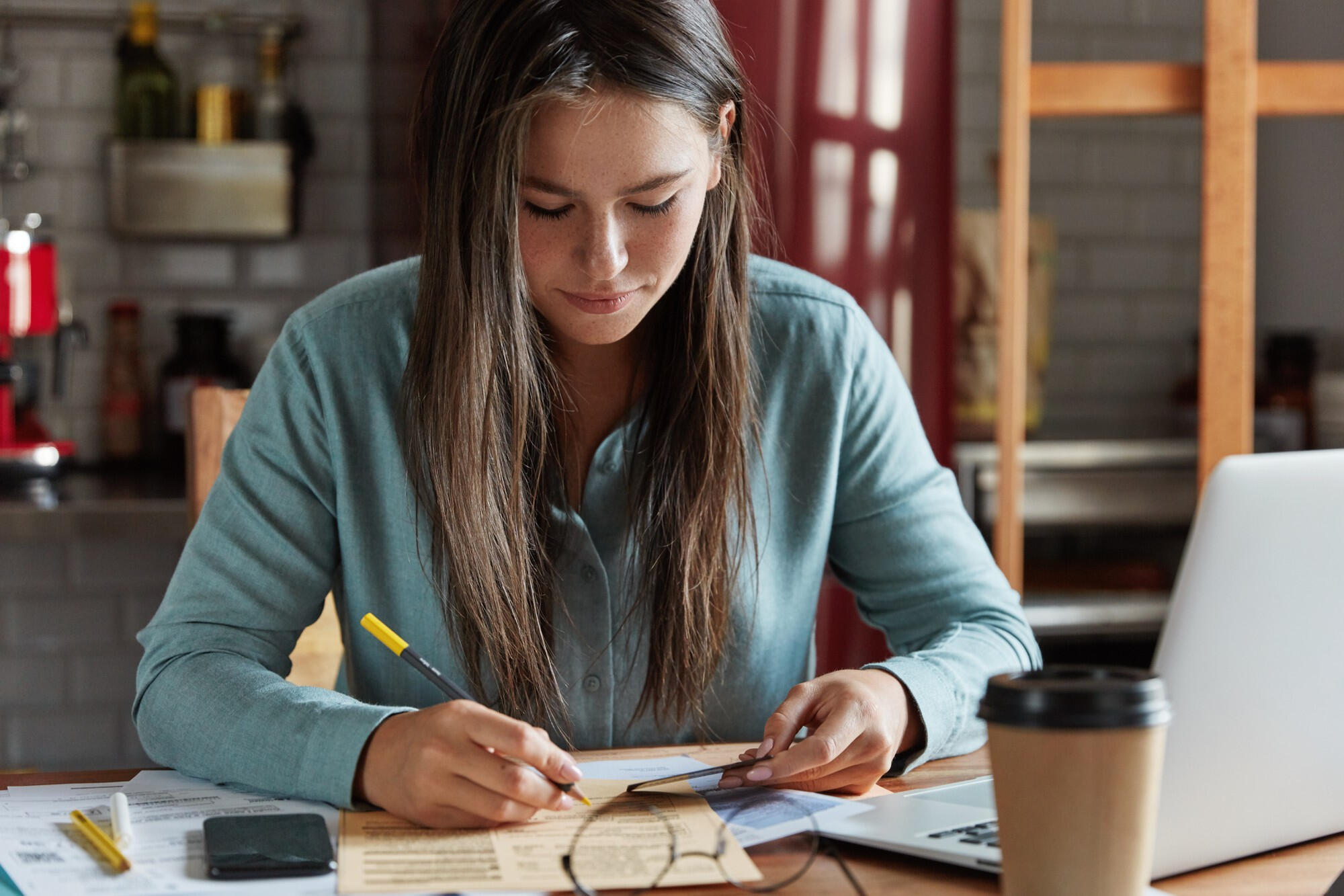 Estudante sentada, lendo e marcando o livro.