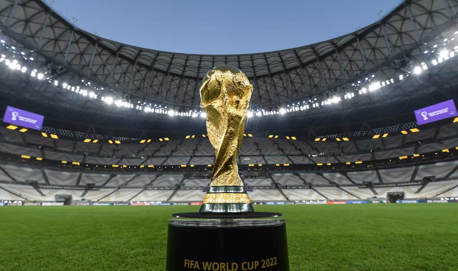 Taça da Copa do Mundo no meio do estádio de futebol.
