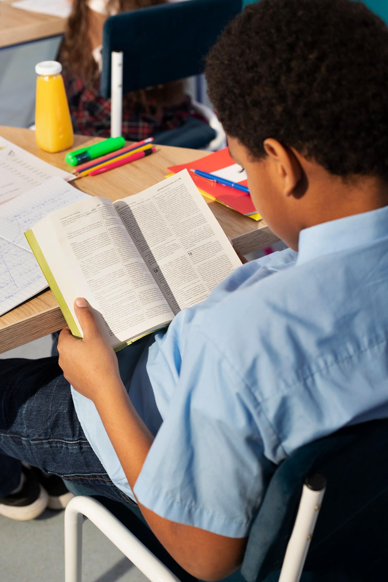 Estudante sentado na cadeira escolar lendo o livro. 