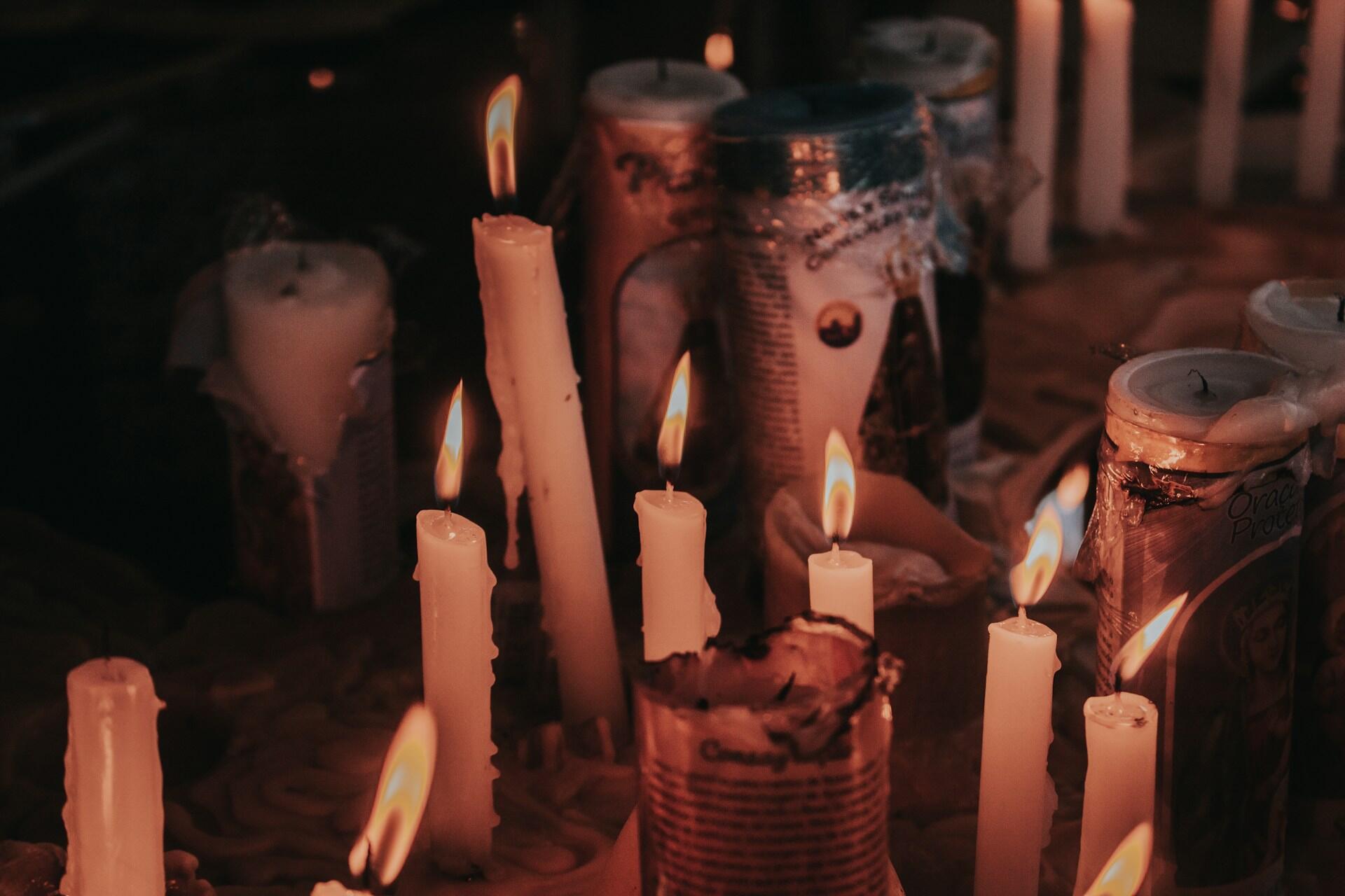 Imagem de velas queimando, uma delas com a imagem de nossa senhora.