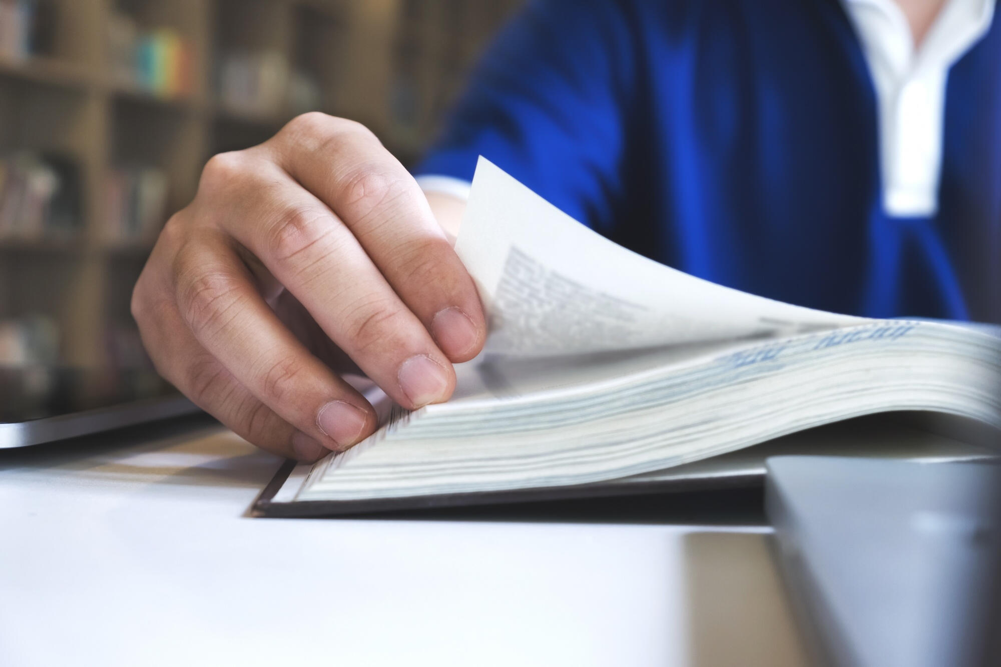 Mão de homem passando a página de um livro.