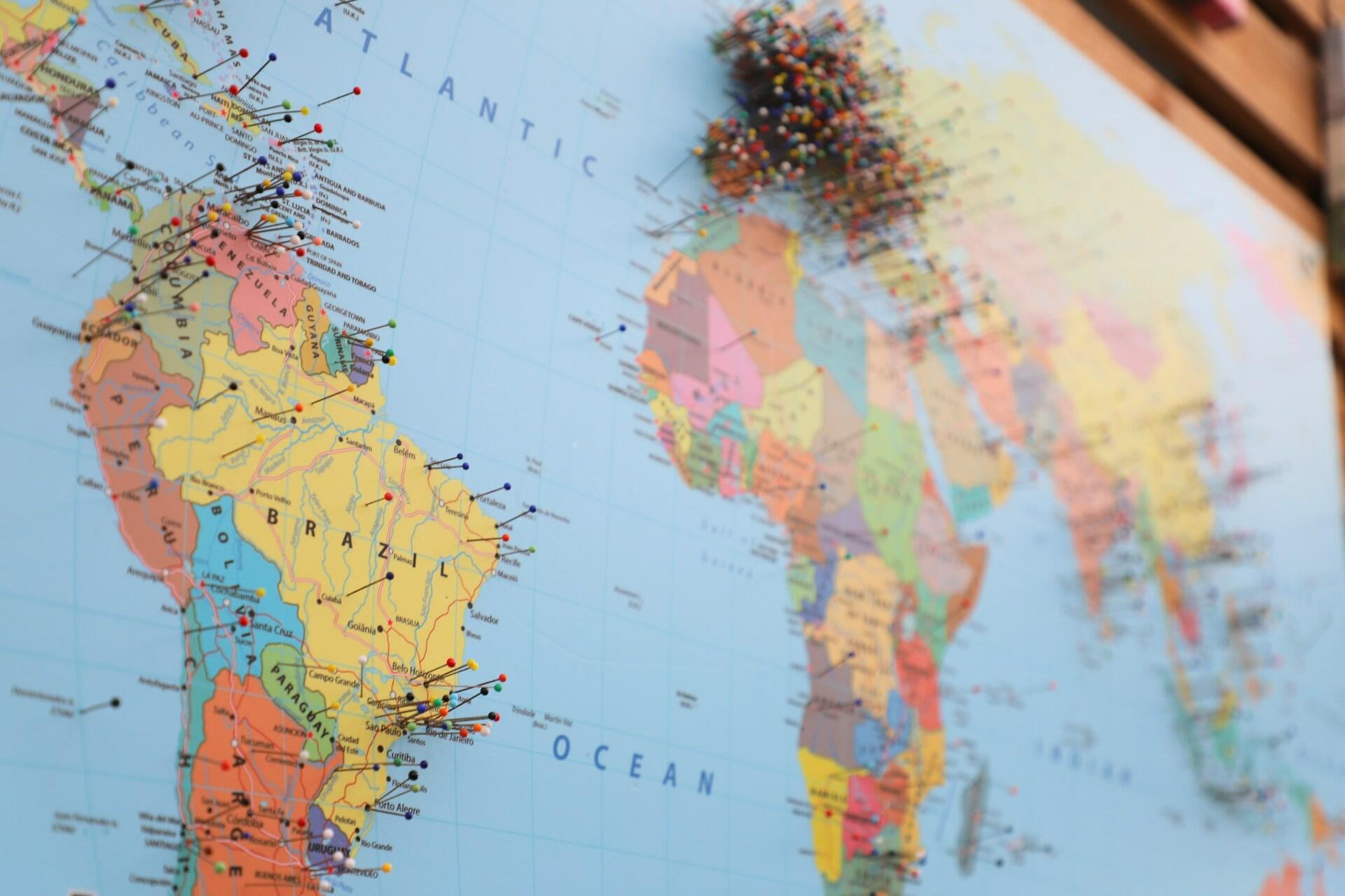Imagem do mapa mundi com alfinetes em alguns países.