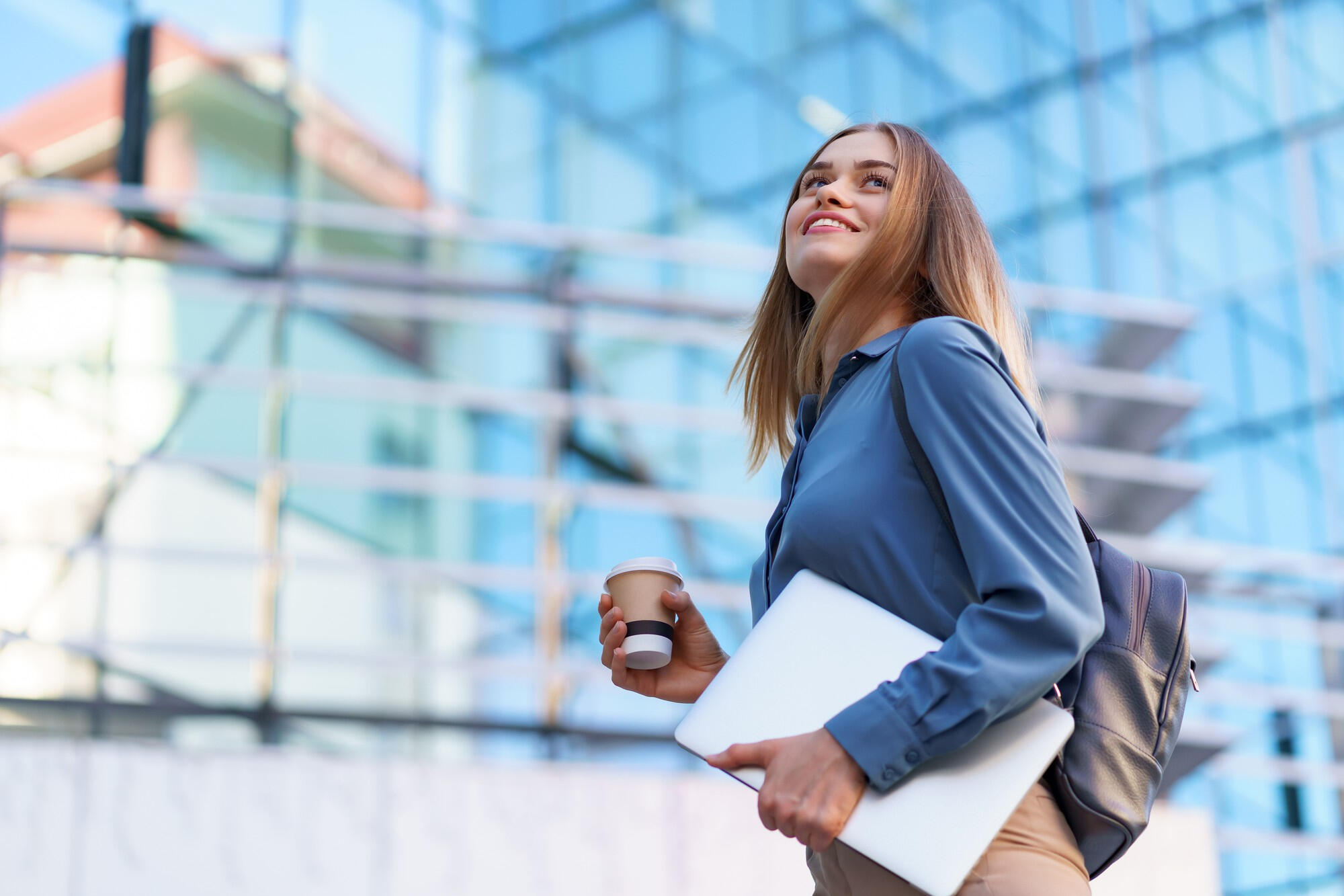 Profissional com café e pasta na mão, andando em direção à empresa.