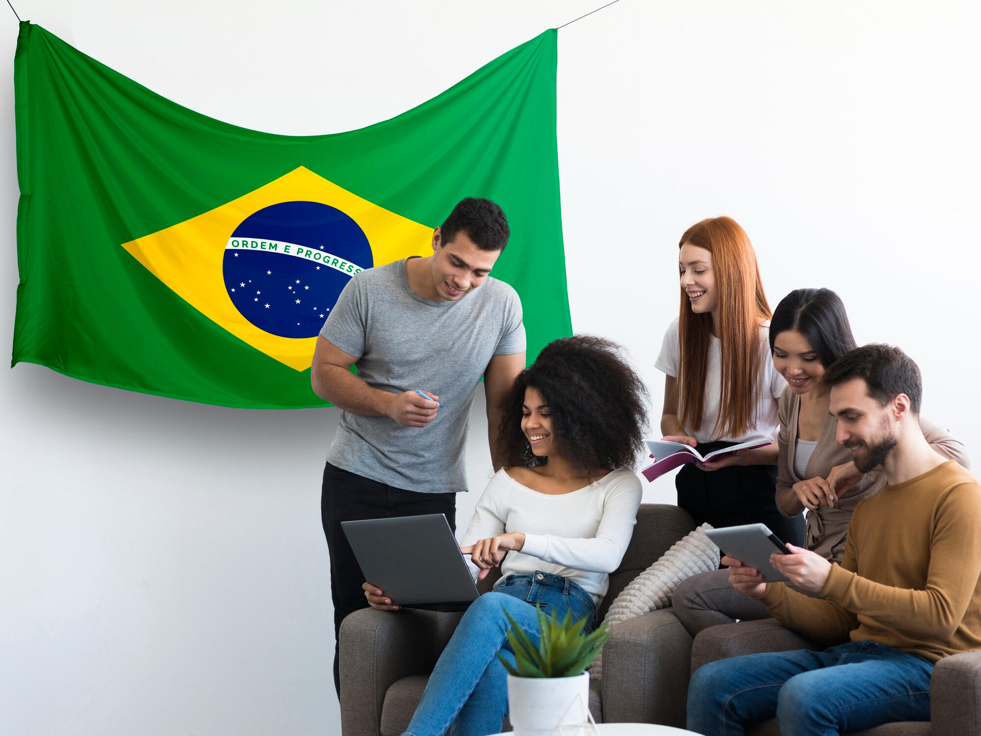 Jovens conversando e vendo informações opr um notebook, com a bandeira do Brasil na parede.