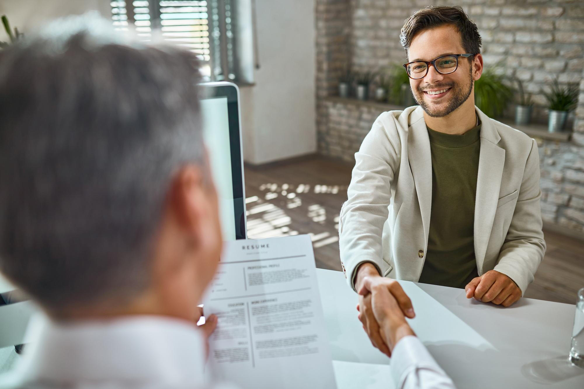 Profissional apertando a mão do chefe, sorrindo e sendo contratado pela empresa.