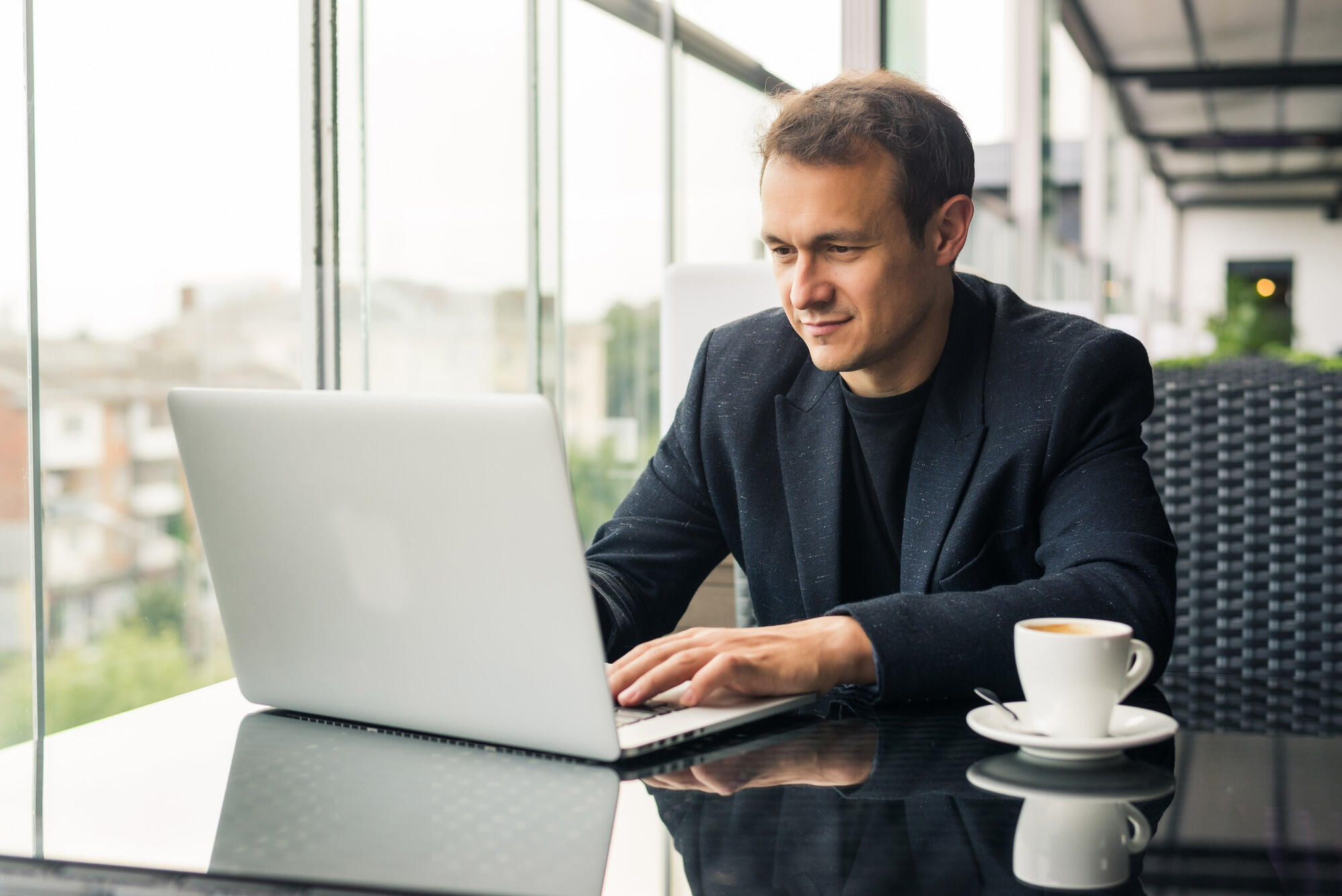 Executivo trabalhando com notebook em cima da mesa e café.