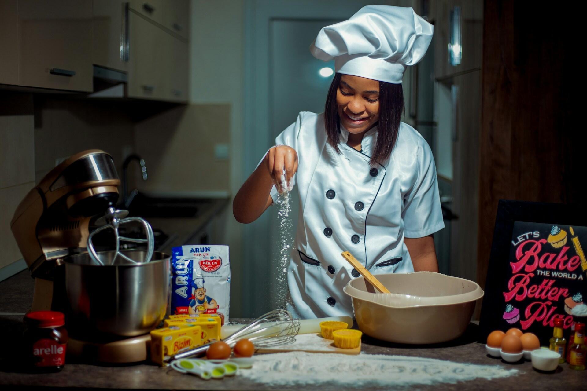 Mulher com roupa de chef fazendo pão.