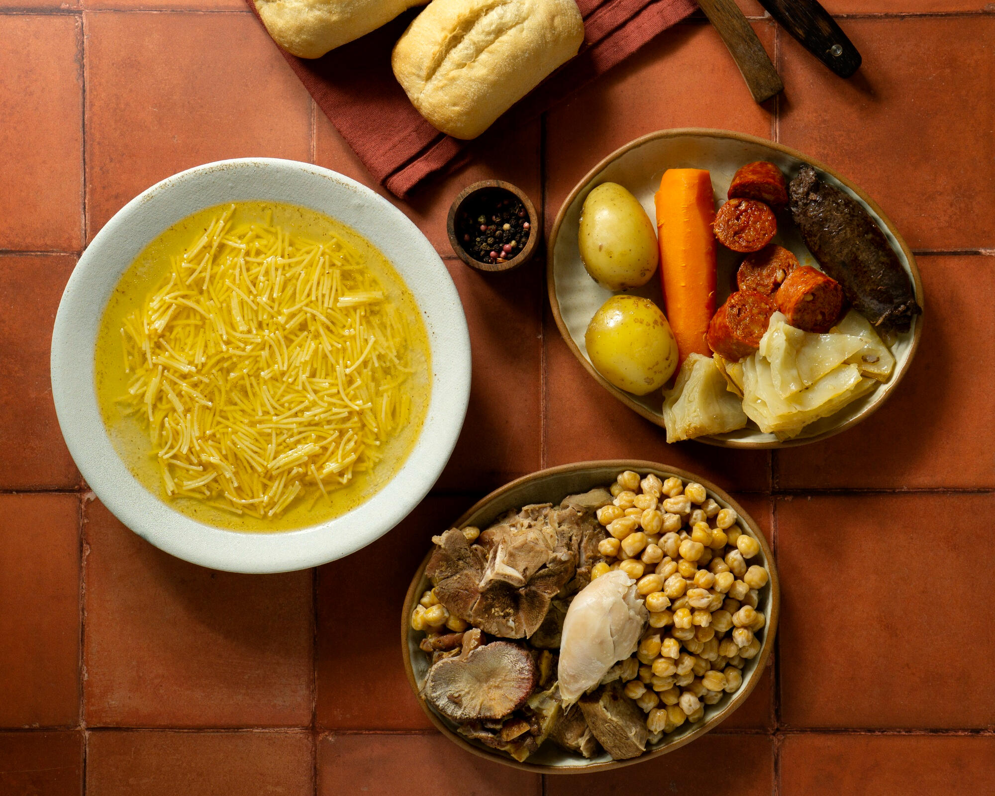 Milho, sopa, cenoura, batata e legumes em pratos em cima da mesa.
