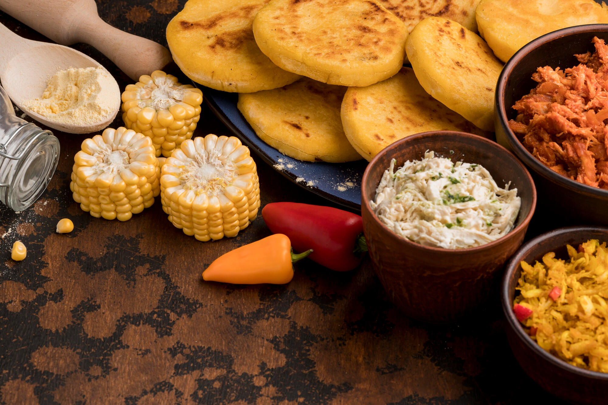Milho, arepas colombianas e outros alimentos em cima da mesa.