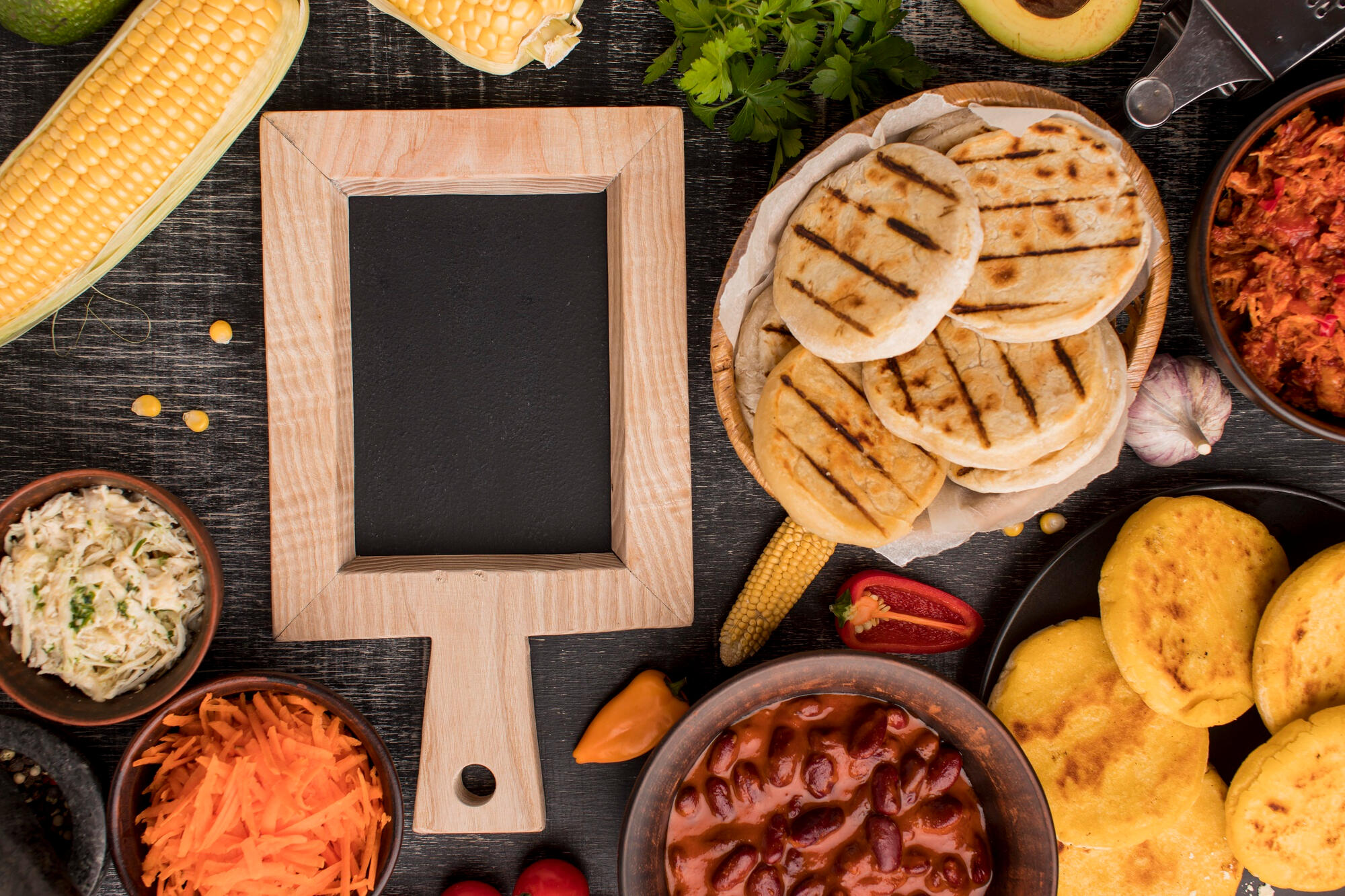 Feijão, cenoura, arepa e outras comidas típicas sul-americanas em cima da mesa.
