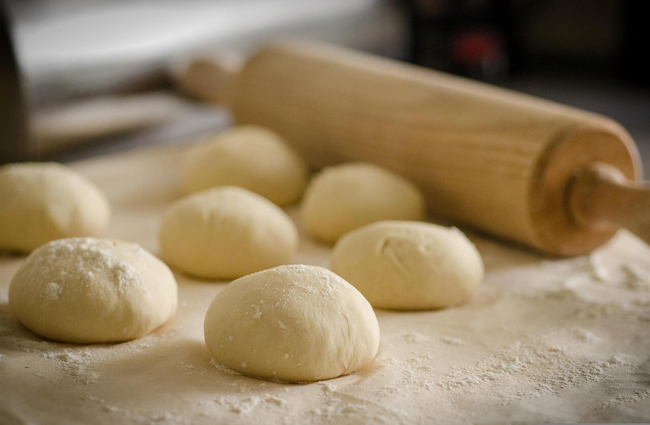 Imagem de pães em formato redondo e um rolo de abrir massas.