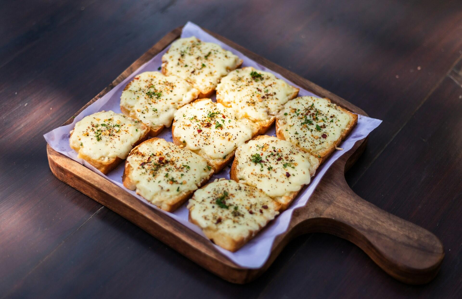 Fatias de pão com queijo e alho em uma tábua