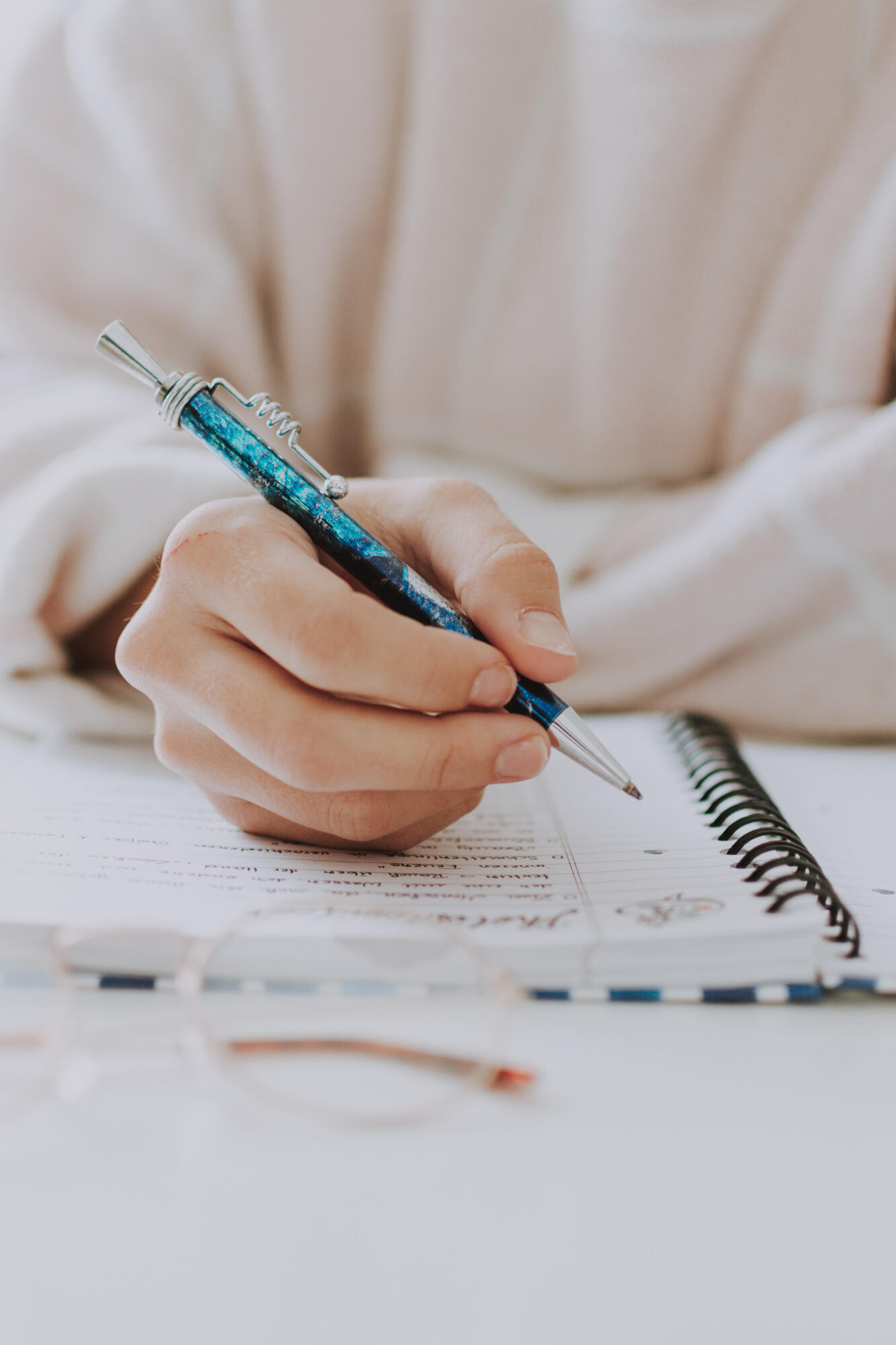 Mulher escrevendo texto em caderno com lapiseira.