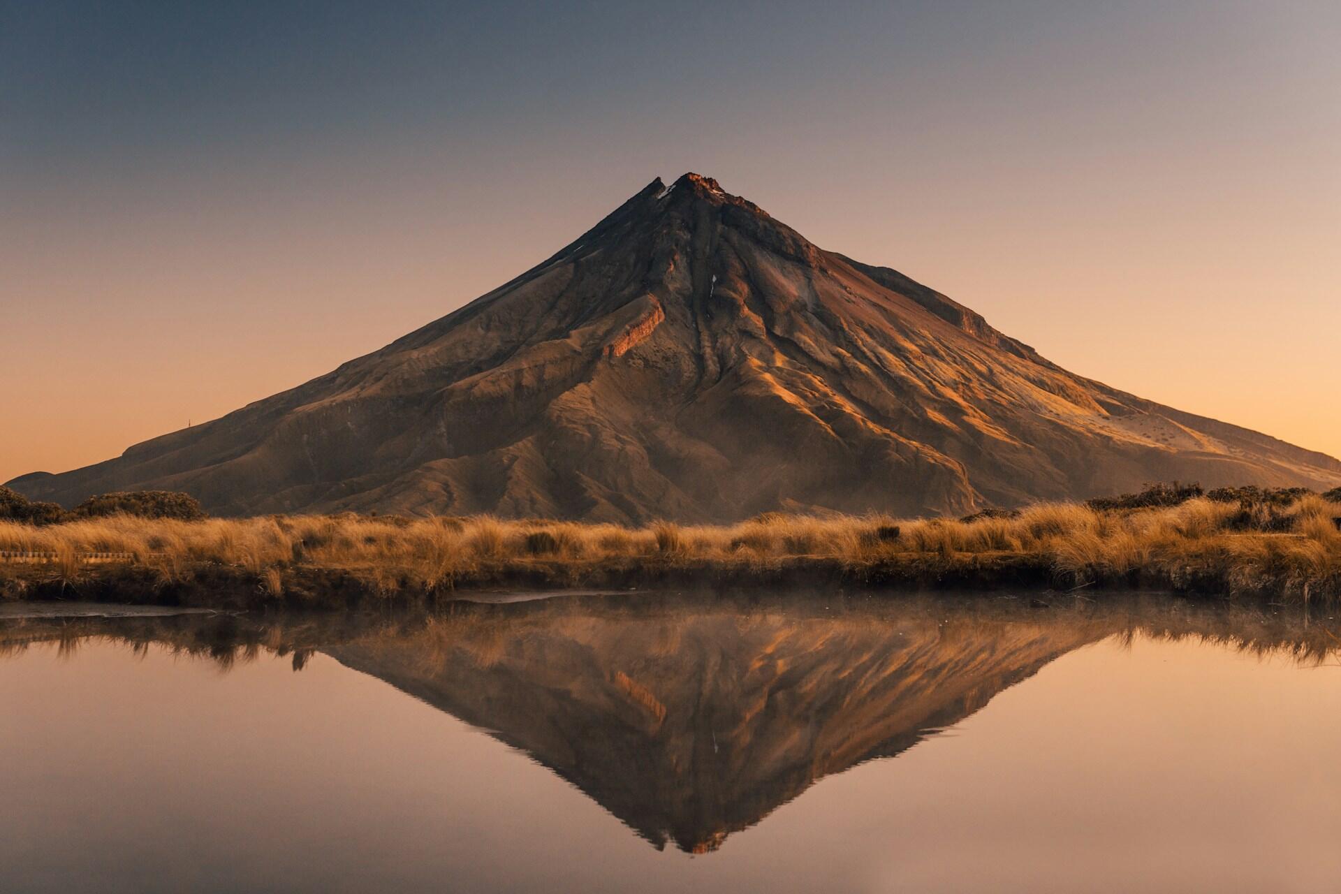 Imagem de um vulcão refletindo em um lago.