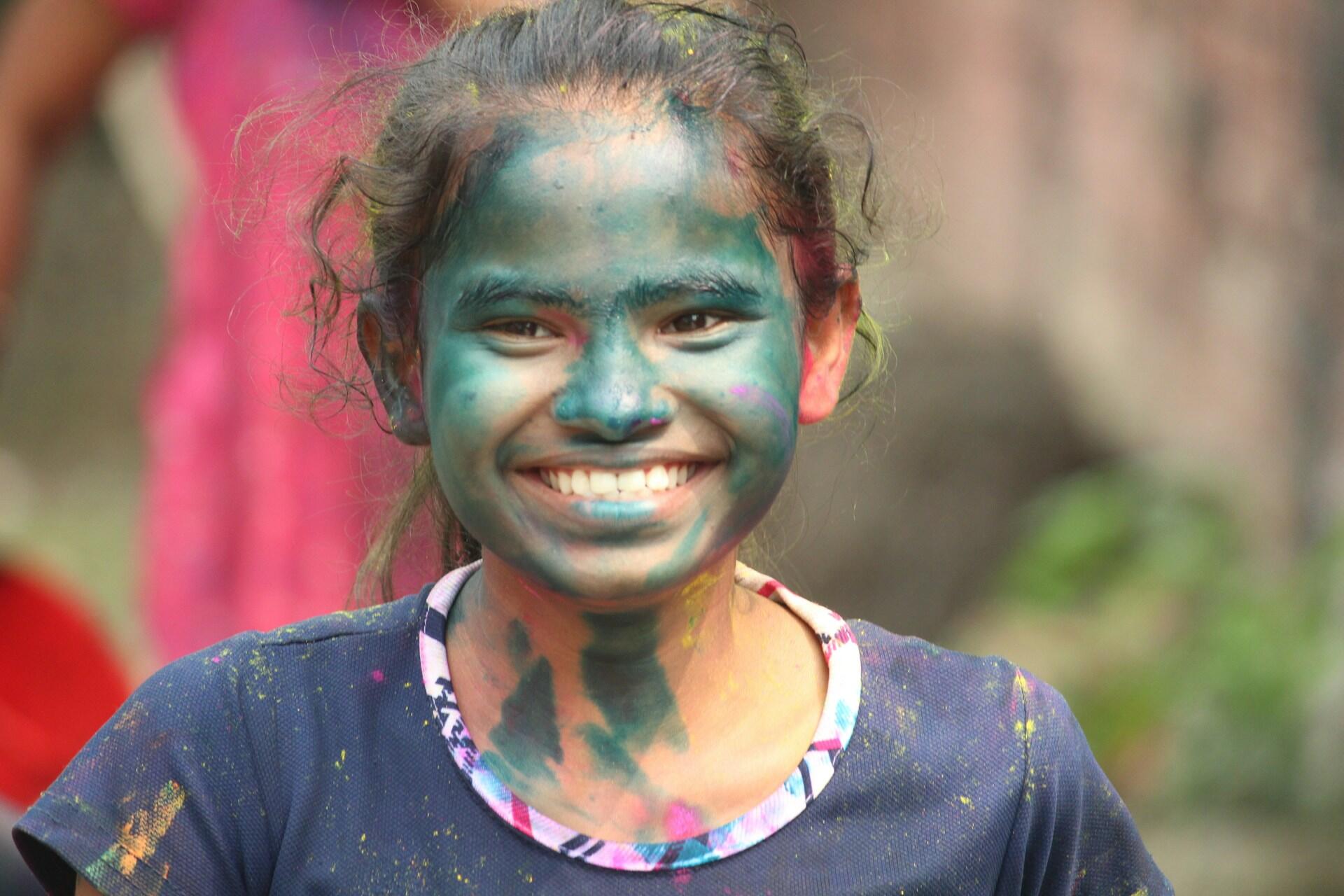 Criança negra pintada colorida brincando e sorrindo tem altas habilidades