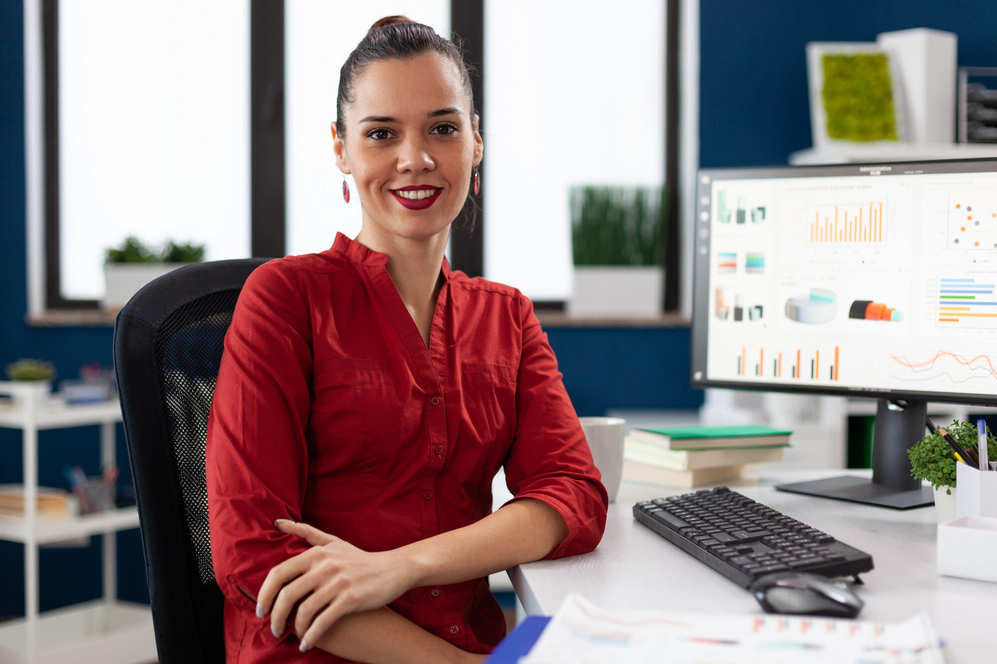 Mulher sorridente com o computador sobre a mesa.