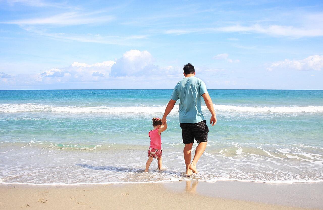 Imagem de um homem e uma criança em uma praia