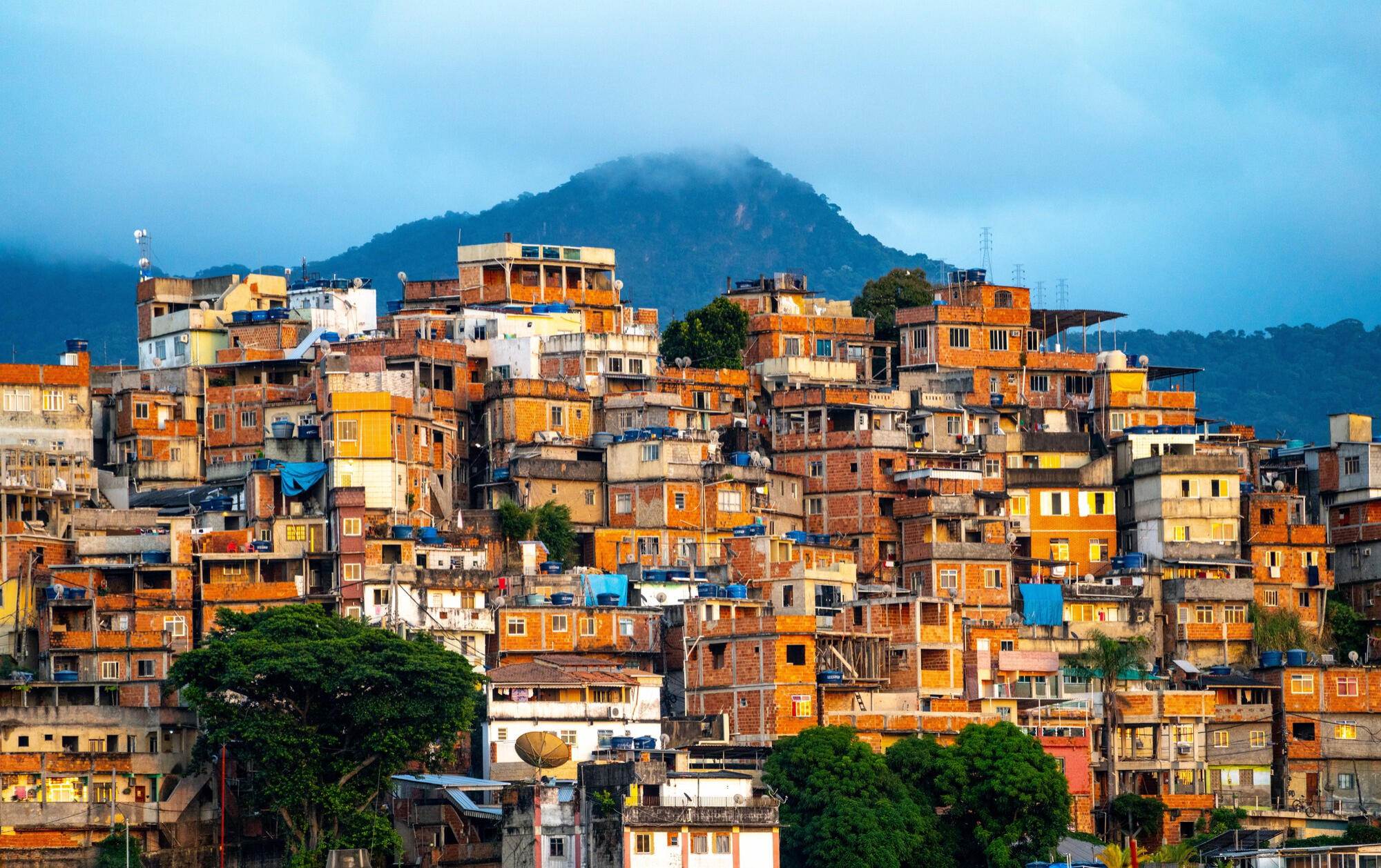 Cidade brasileira, casas e montanha ao fundo de tarde.