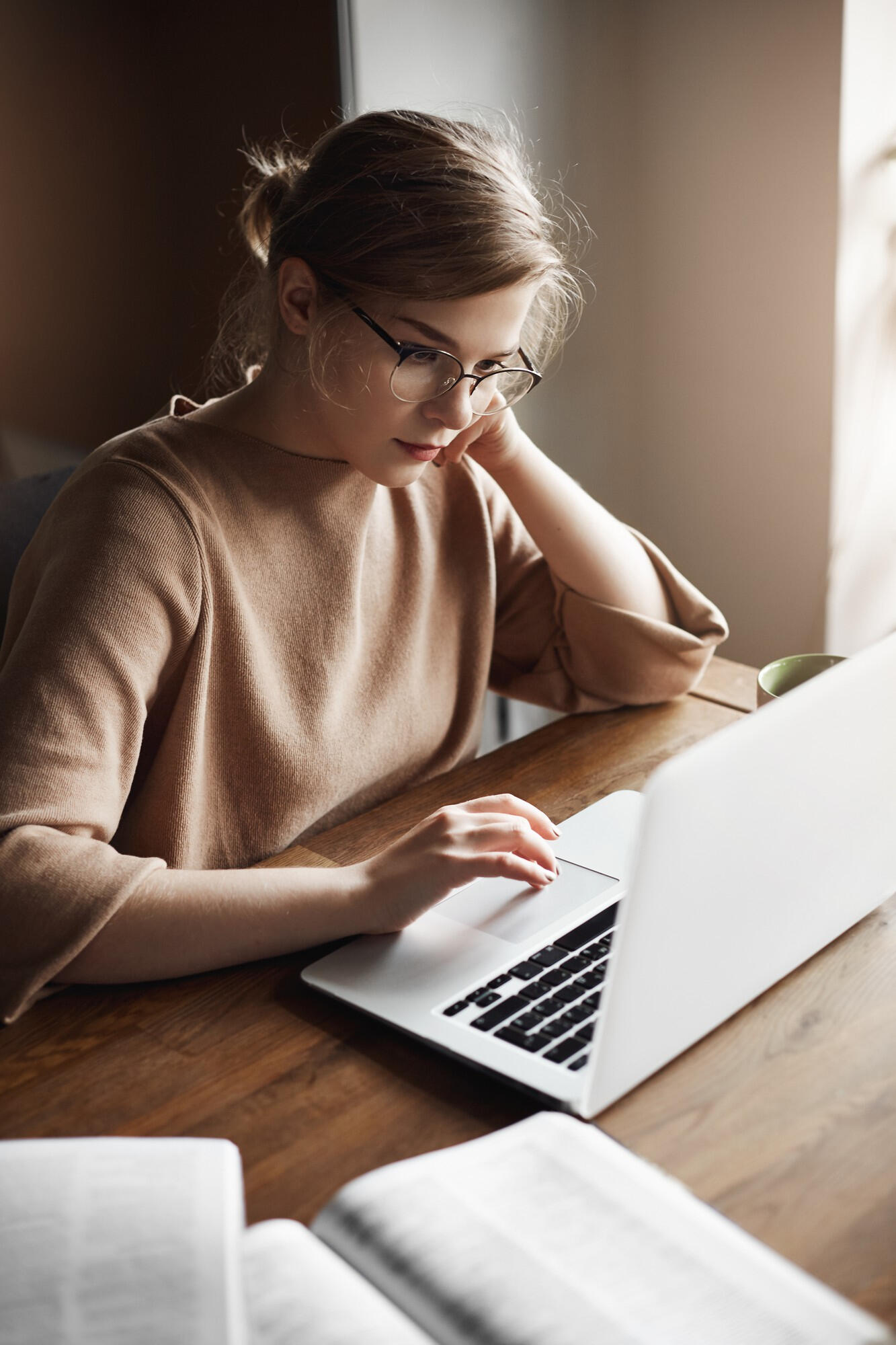 Estudante estudando com notebook e livro sob a mesa.