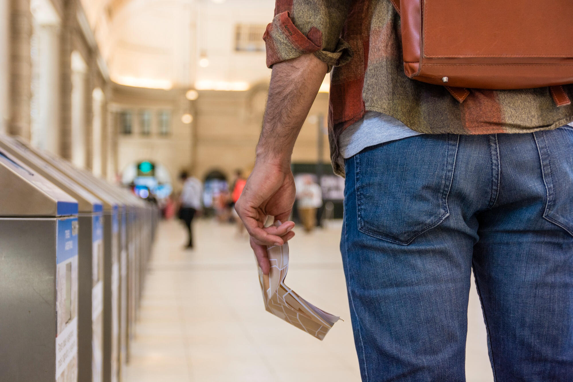 Pessoa com mochila nas costas e segurando dinheiro, em pé, no aeroporto.
