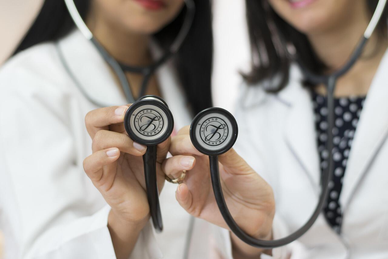 Imagem de duas médicas segurando um estetoscópio.