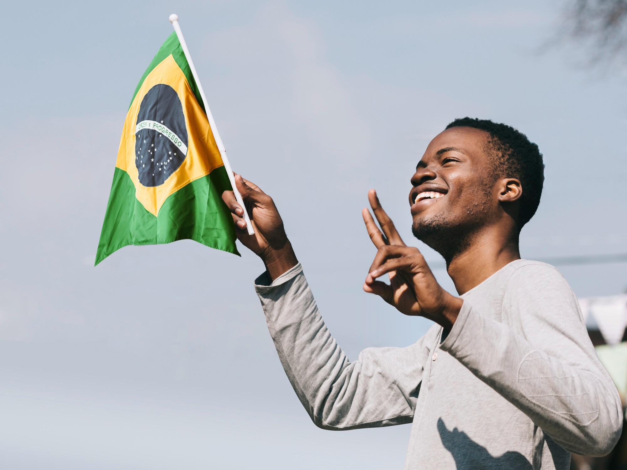 Menino sorridente balançando a bandeira do Brasil.