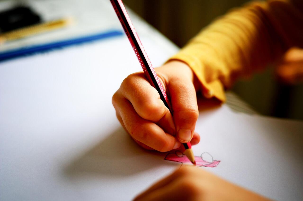 Imagem de uma criança desenhando em uma folha de papel