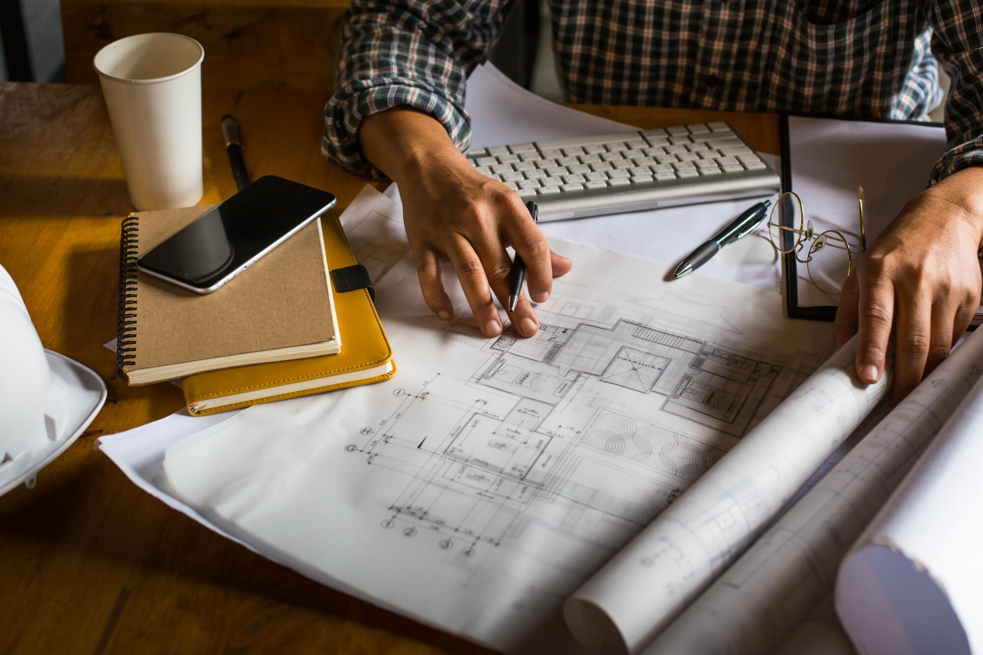 Mão e uma pessoa criando desenho de arquitetura em um papel.