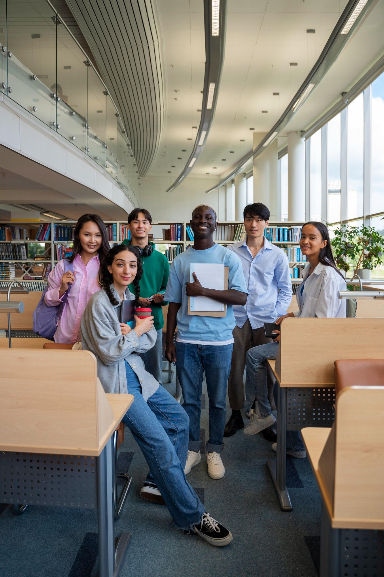 Alunos em pé e em uma biblioteca da faculdade.