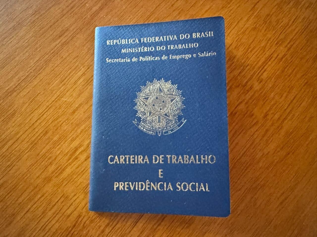 Imagem de uma carteira de trabalho fechada sobre uma mesa