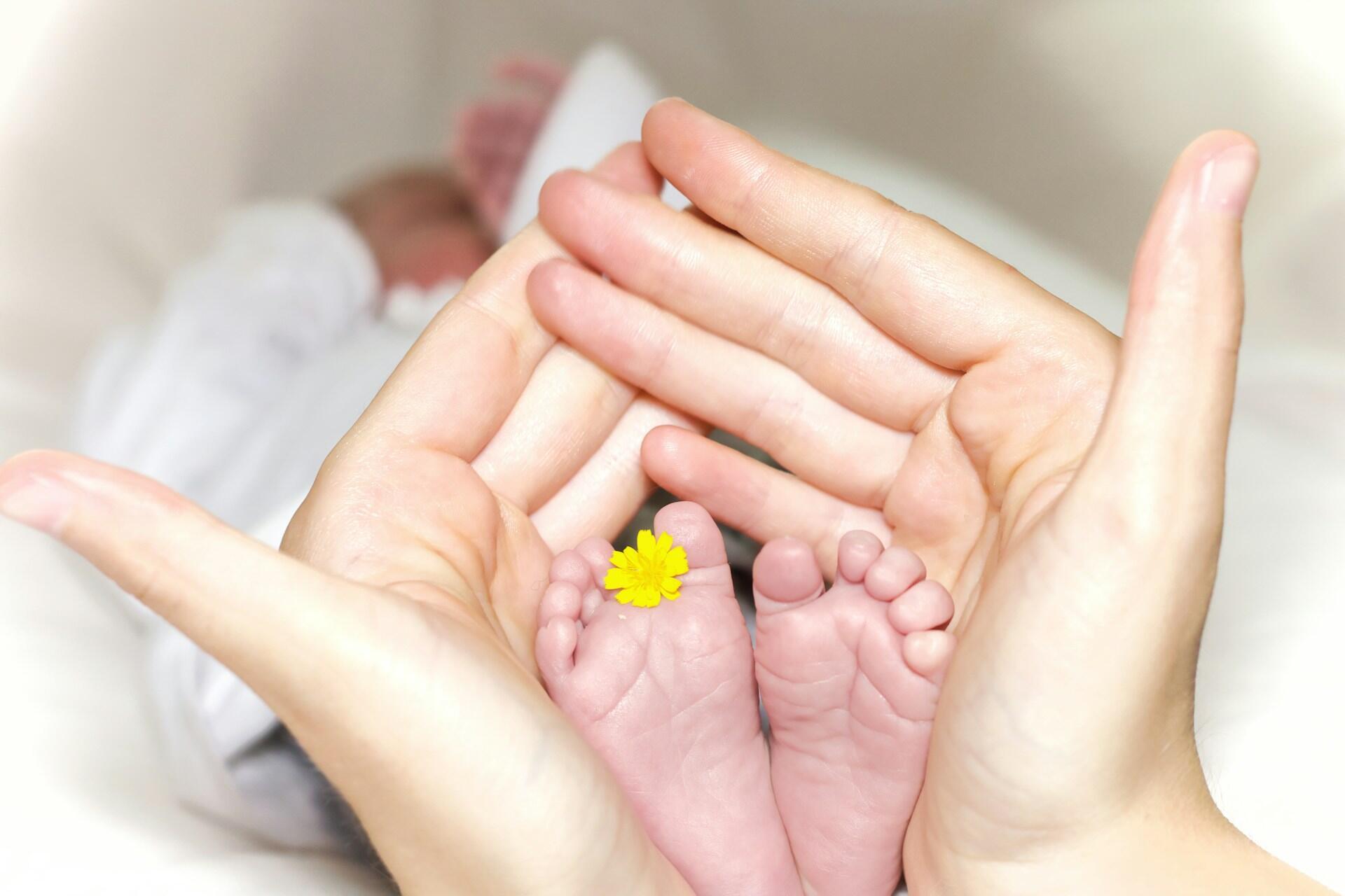 Imagem de uma mão segurando os pezinhos de um bebe