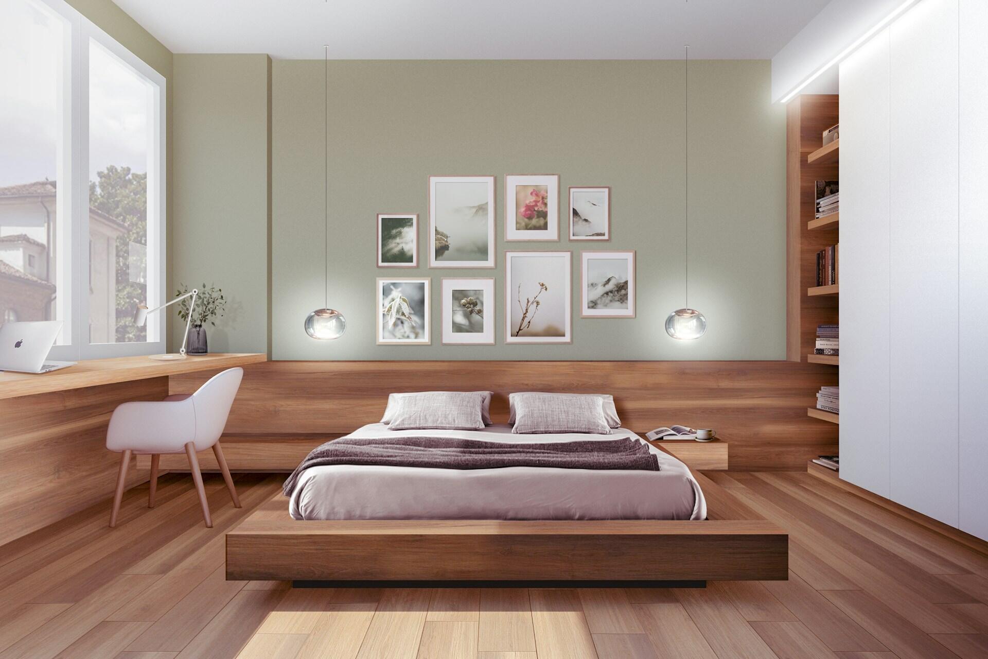 Modern bedroom with a low wooden platform bed, matching headboard, sage green accent wall, gallery of framed art prints, two pendant lights, and an integrated desk space by the window.