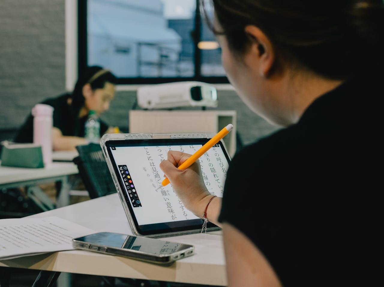 A person using an iPad with a stylus to write, surrounded by study materials in a collaborative workspace.