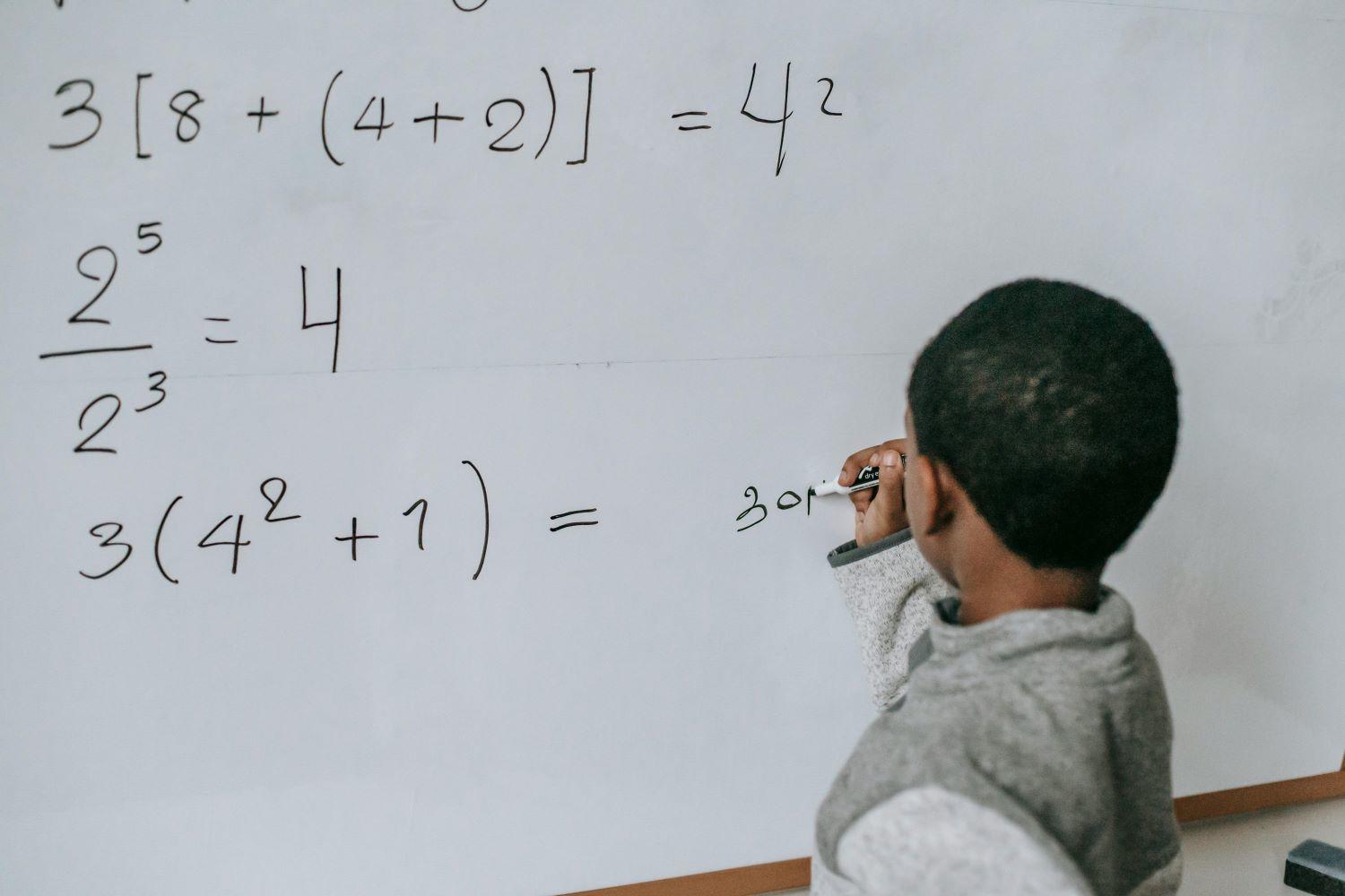 Grirl writing on the white board. Source: Pexels