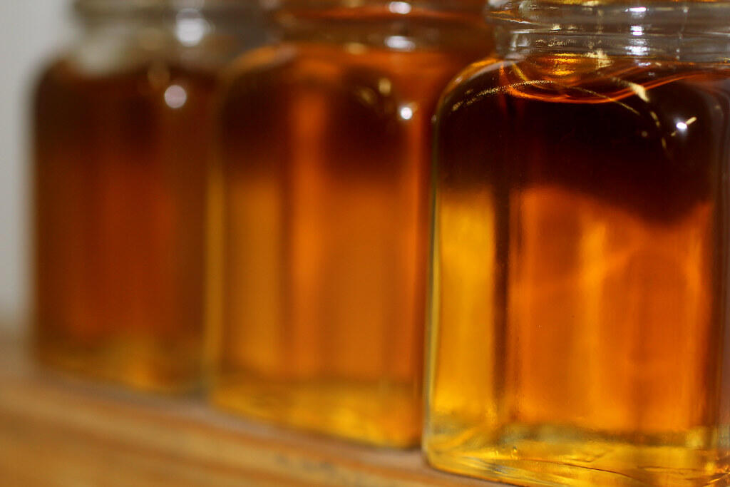 Glass jars filled with golden-brown syrup arranged in a row.