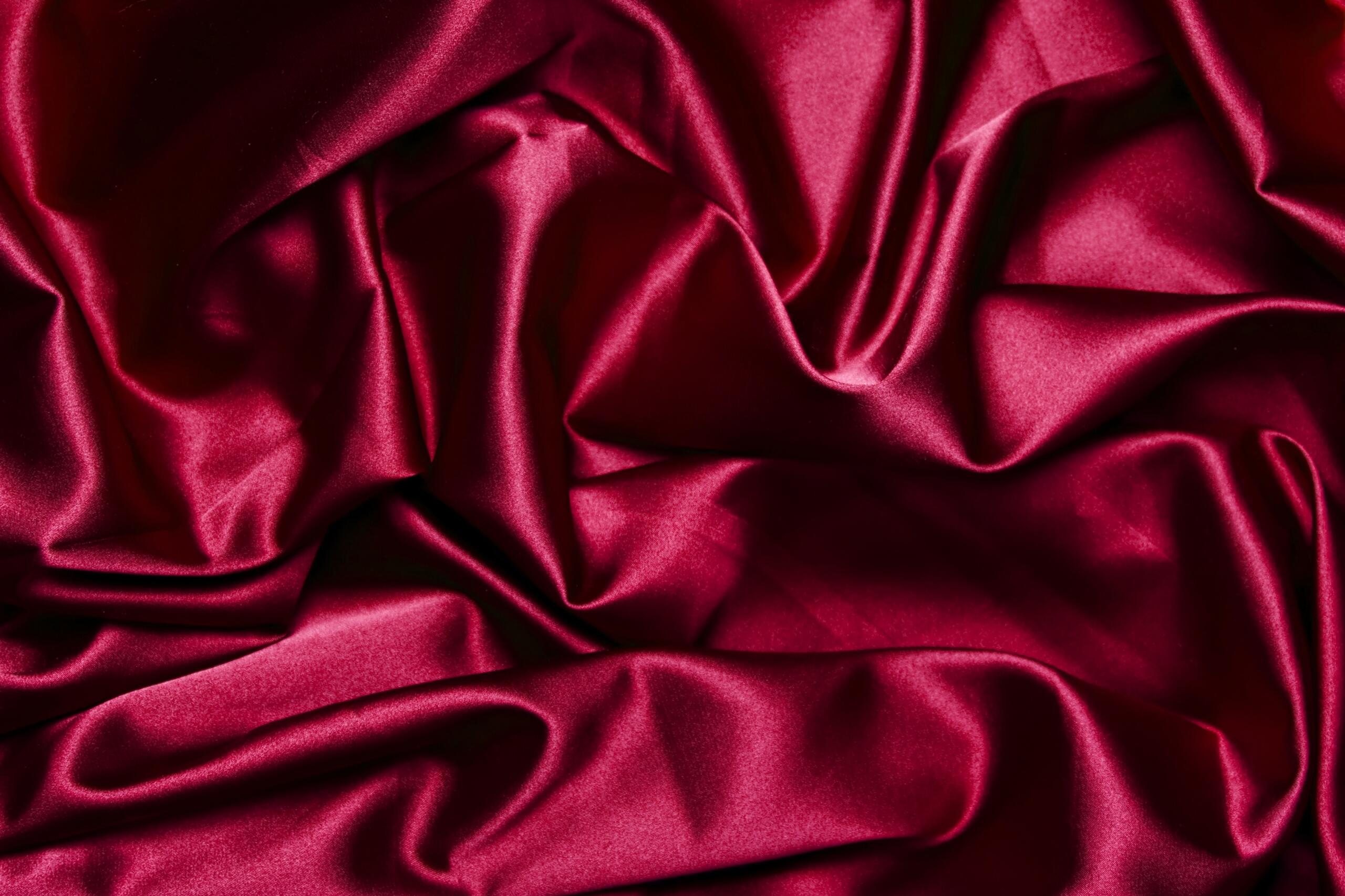 Close-up of rich red satin fabric with soft folds and a glossy finish.