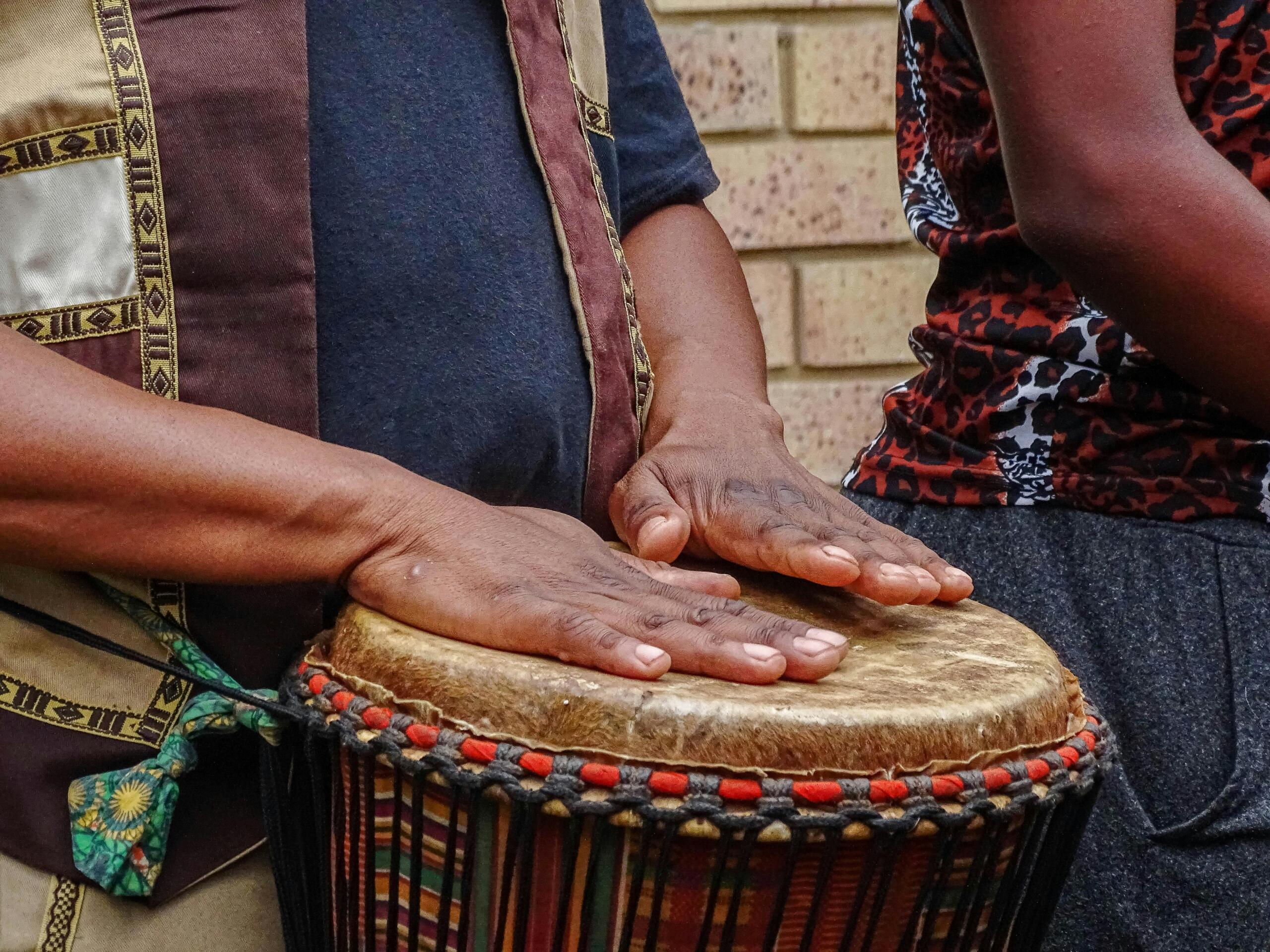 Hands of a drummer playing a colorful djembe drum during a cultural performance.