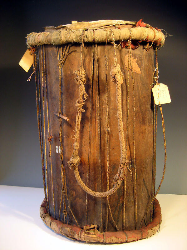 A weathered ancient drum made of wood and hide with rope tensioning, likely from early human history.