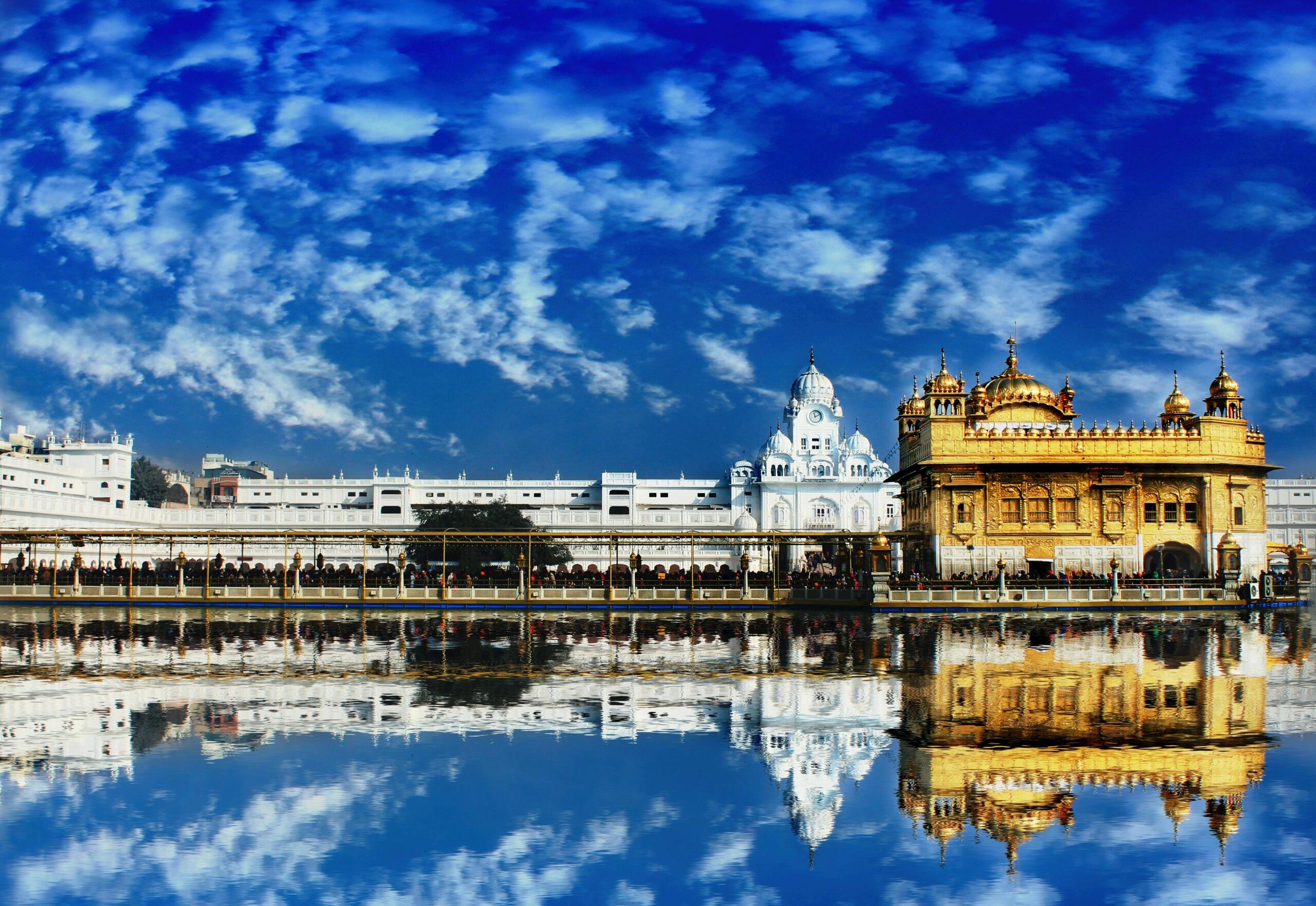 White and gold buildings in India with ornate architectural details, domes, and arched windows, set against a sunny sky.