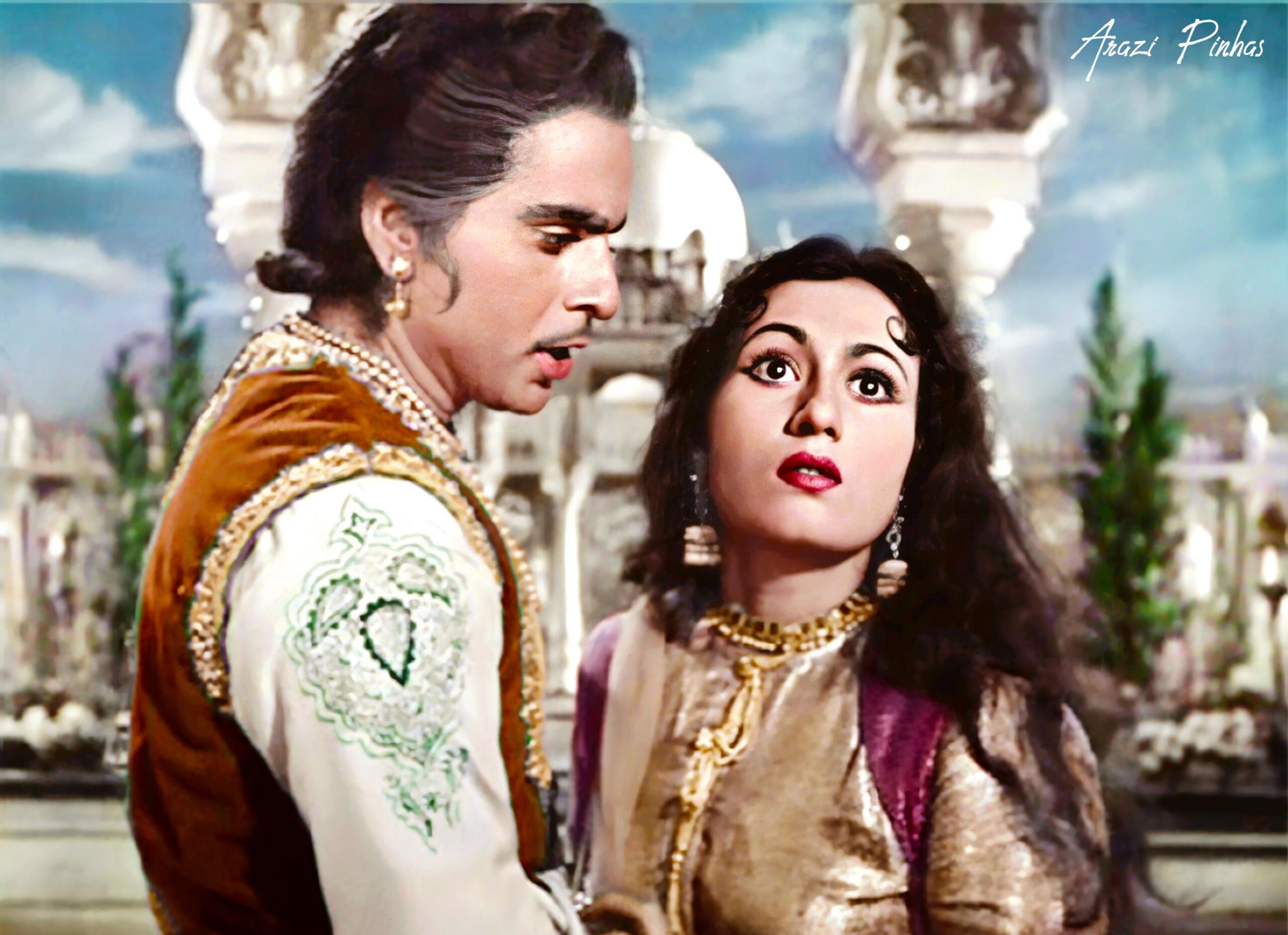 Colorized still from the classic Bollywood film Mughal-e-Azam showing Dilip Kumar as Prince Salim and Madhubala as Anarkali in an intense moment, set against an ornate Mughal palace backdrop.