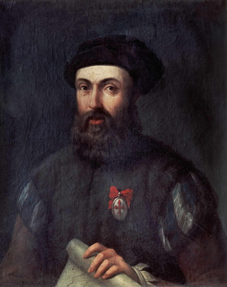 A painted portrait of a bearded man in dark Renaissance-era clothing and a black hat, holding a map or scroll. He wears a medal with a red cross and ribbon on his chest, suggesting a figure of historical or exploratory significance.