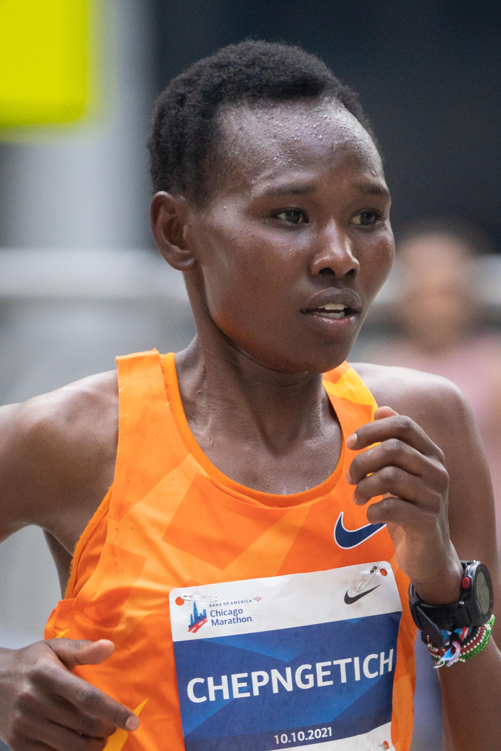 Ruth Chepngetich running in the 2021 Chicago Marathon, wearing an orange Nike singlet and bib with her name.