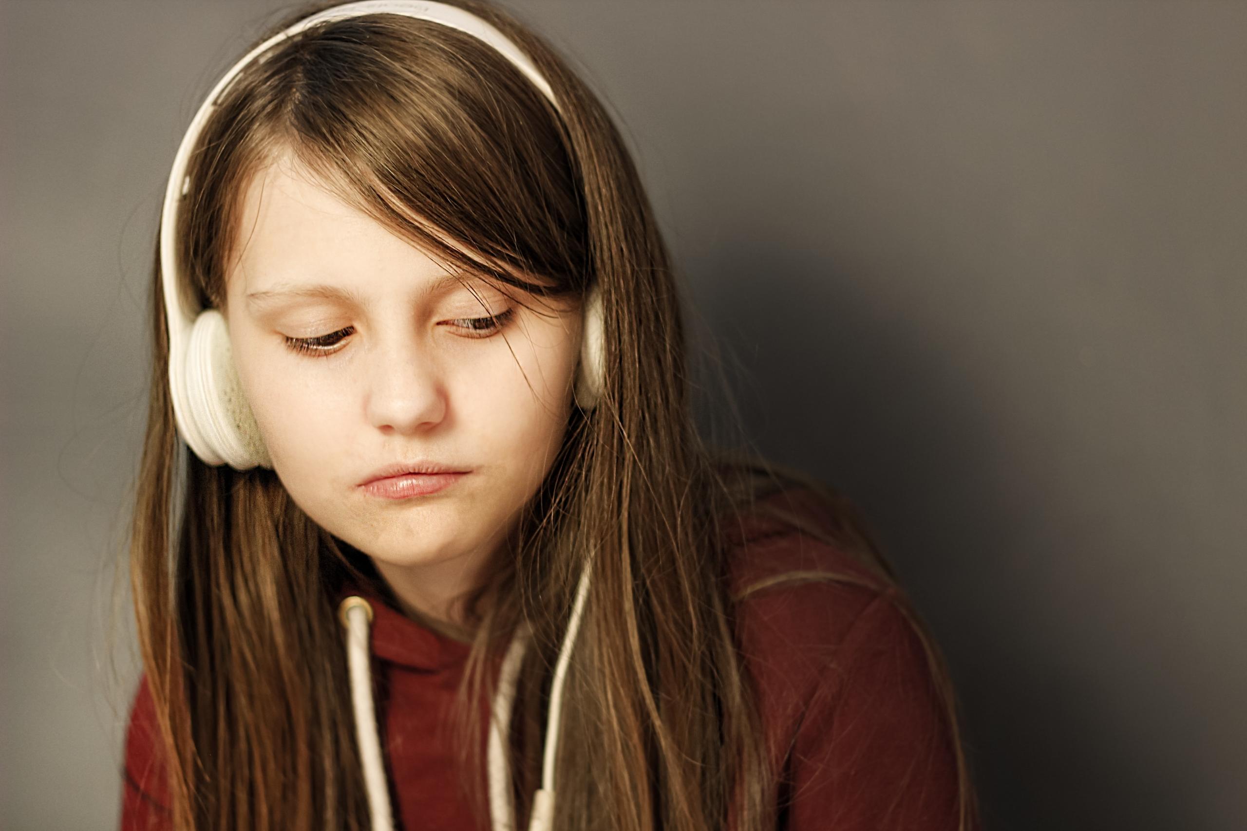 a girl listens to her headphones looking bored